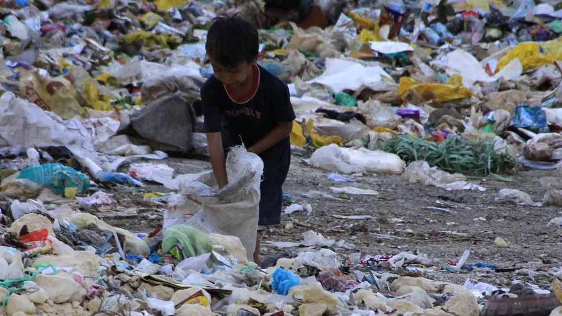 Ein philippinisches Kind sucht auf der Müllkippe nach Essen.